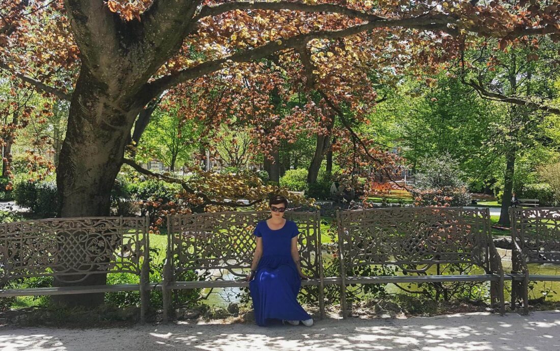 Woman in blue pausing in Jardin Royal Toulouse