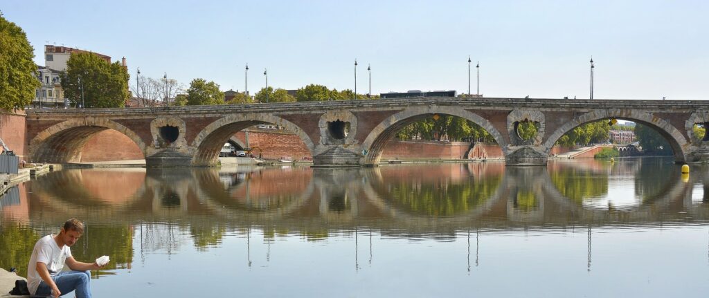 Man sitting on Pont Neuf bridge in Toulouse