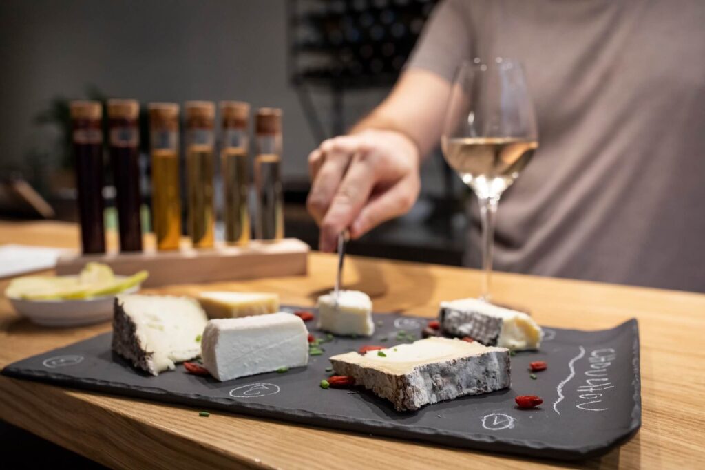 man cutting cheese on board with cheese and wine