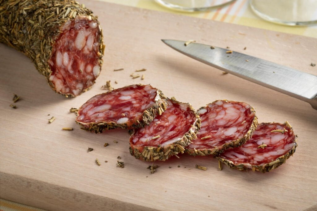 Traditional French sausage and slices covered with herb de provence on a cutting board